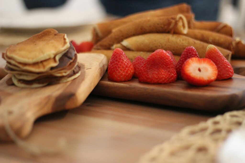 Close-up of pancakes and fresh strawberries on wooden boards, showcasing a sweet breakfast treat.